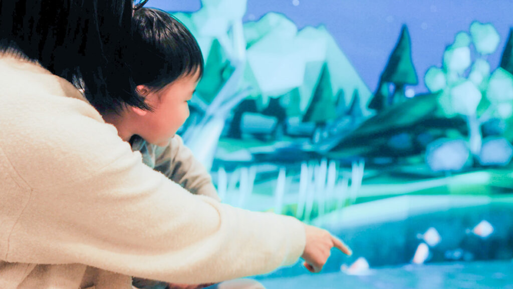 フラクト：フレスポ若葉台のインタラクティブな床用LEDで泳ぐ魚を見つめる子ども